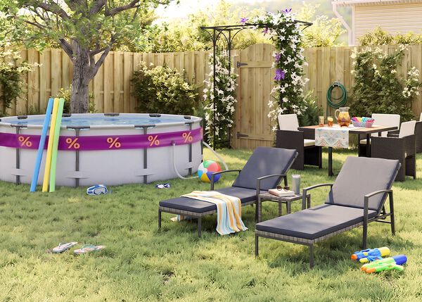 Sunny backyard garden with an above-ground swimming pool, pool noodles, goggles, beach ball, and flip-flops on the grass. Two black metal sun loungers with grey cushions sit beside a small side table, while an outdoor dining set with dark rattan chairs is arranged near a flowering pergola, wooden fence, garden plants, and summer party accessories.
