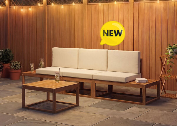 New three-seat modular outdoor sofa with cream cushions and a matching low coffee table, set on a stone patio against a warm wooden wall, NEW badge displayed