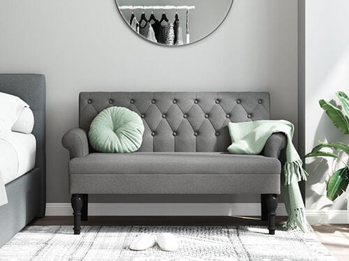 Grey upholstered 2-seater sofa in a styled bedroom. Click to see the products.