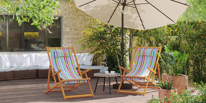 Colourful folding beach chairs and outdoor umbrella on a patio. Click to shop the collection.