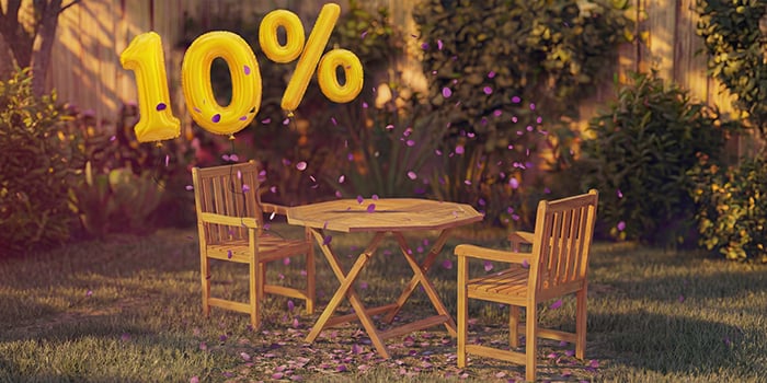 Wooden outdoor dining table with two matching chairs in a garden setting, decorated with pink confetti and golden 10% discount balloons, highlighting a seasonal sale on outdoor dining furniture.